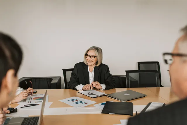 A professional business meeting with diverse professionals discussing reports in a modern office setting. Intern kontroll i finansfunktionen: rutiner, roller och uppföljning